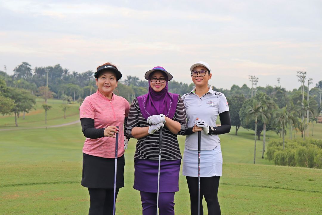 Three Ladies Posing for a Photograph with the golf course background