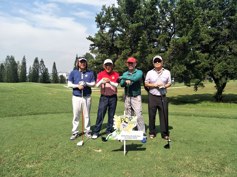 A group of 4 gentleman posing for a picture at the golf filed 