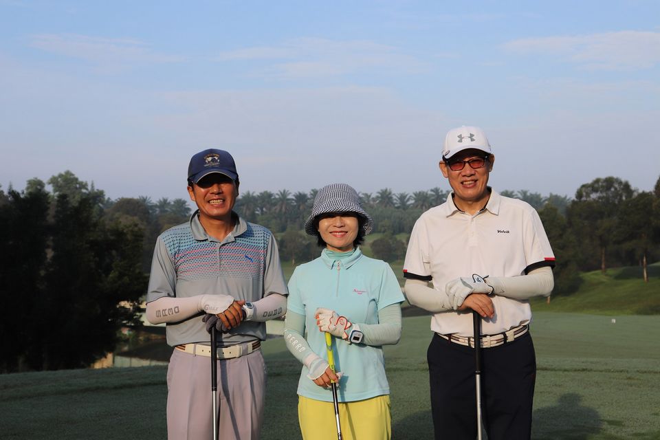 Three golf players posing for a photograph at the golf field