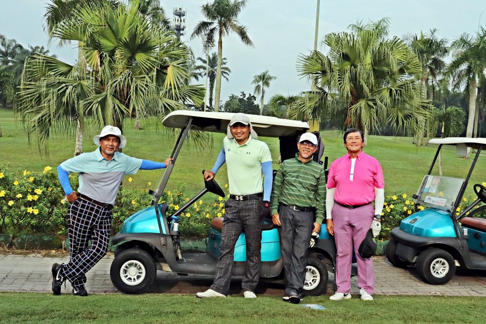 A group of gentleman posing in front of golf cart 