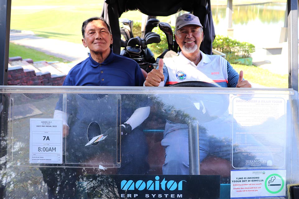Two gentlemen sitting inside a golf cart 