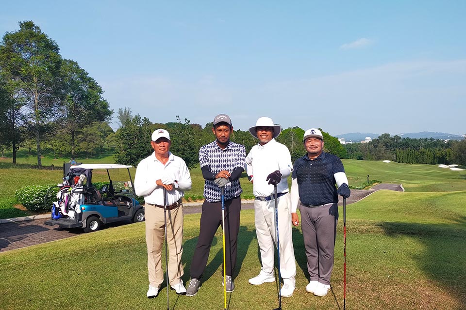 A group of 4 gentleman posing for a picture at the golf filed 